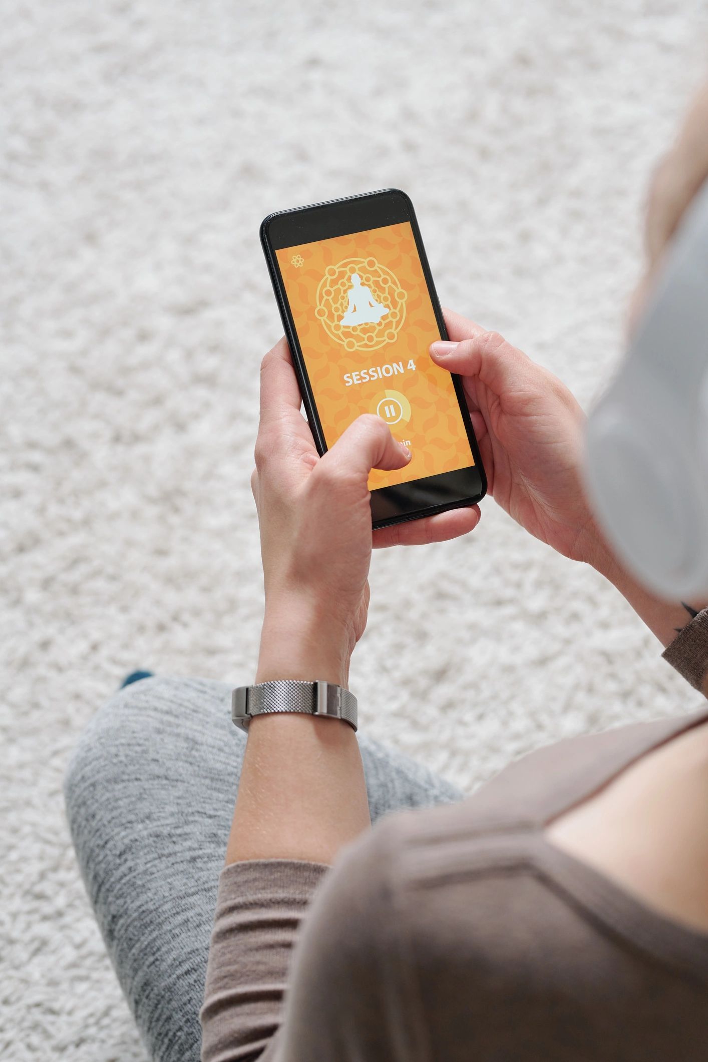 Hands holding a phone while listening to an audio meditation lesson