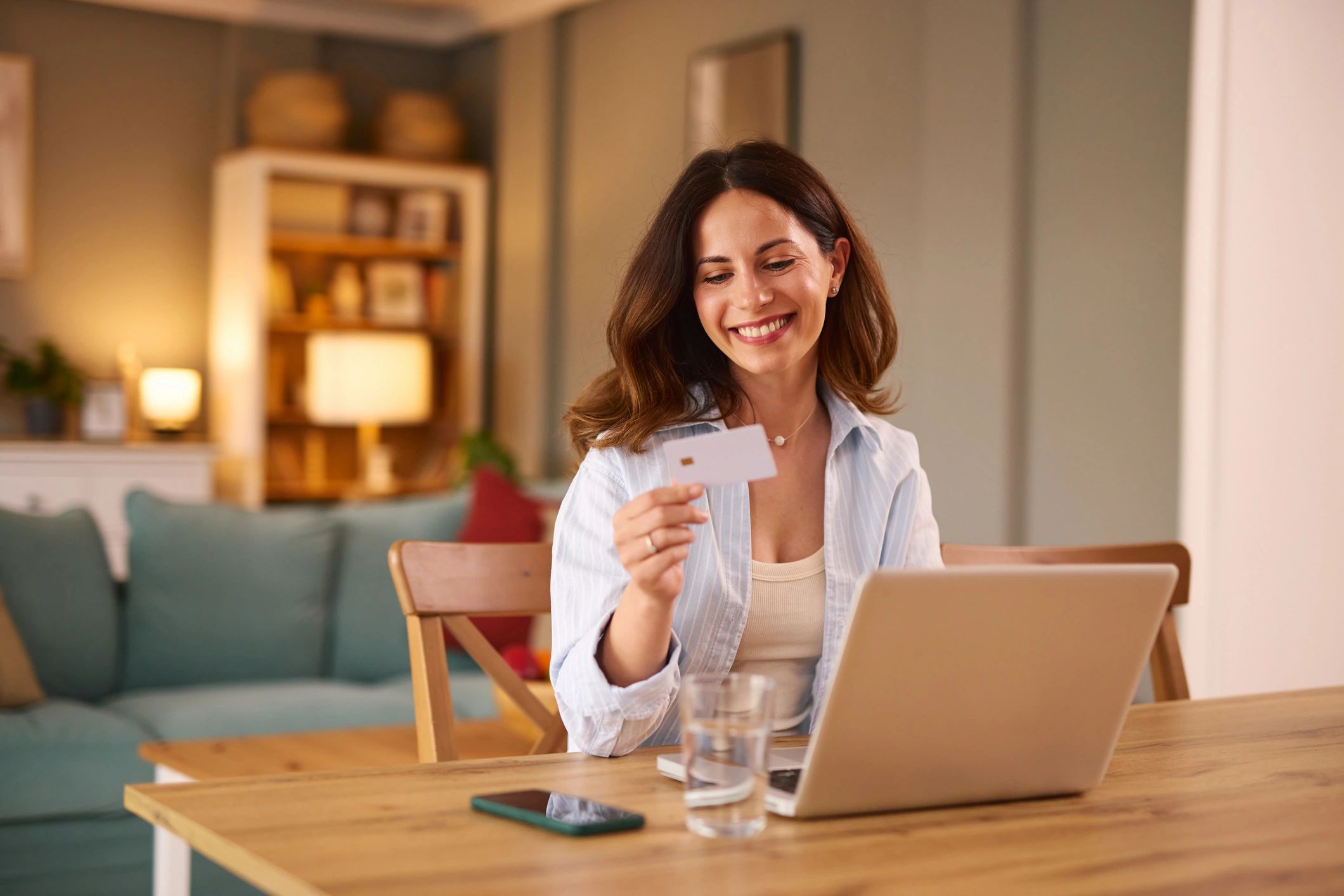 Smiling woman paying online with a credit card at home