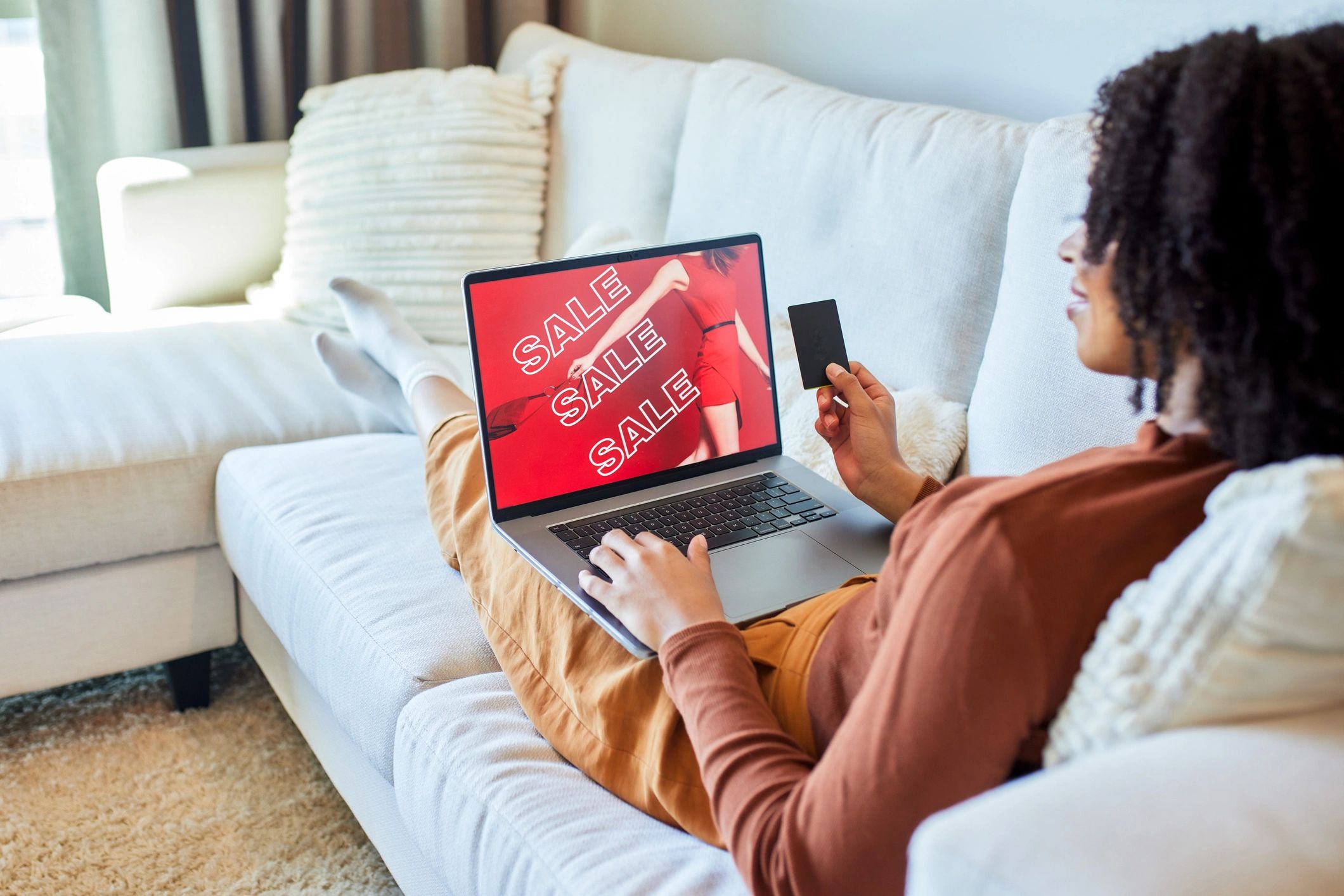 Woman shopping online with laptop and credit card on a sofa