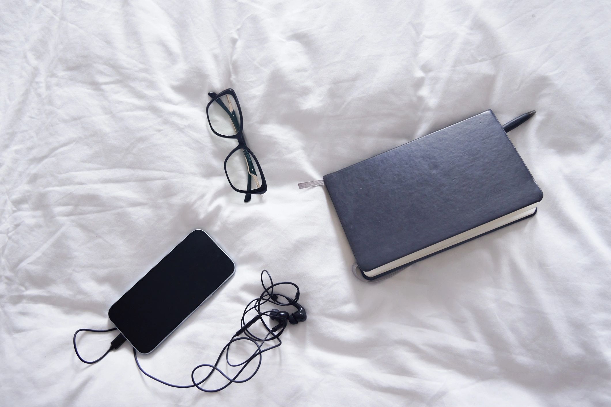 Journal and glasses on bedding representing self-help and reflection